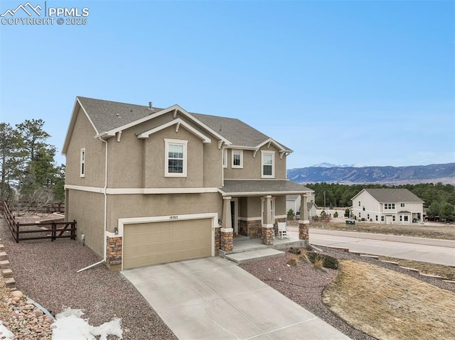 view of front of house with stucco siding, driveway, stone siding, a mountain view, and covered porch