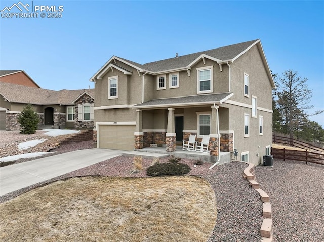 view of front facade with stucco siding, stone siding, fence, covered porch, and a garage