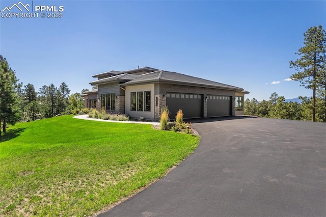 view of front facade with an attached garage, aphalt driveway, and a front yard