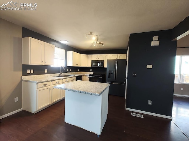 kitchen featuring light countertops, white cabinets, a sink, black appliances, and baseboards