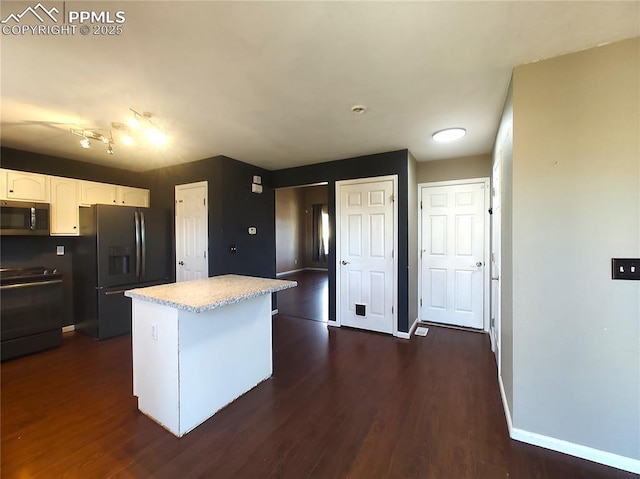 kitchen featuring baseboards, a kitchen island, dark wood-style flooring, black appliances, and white cabinetry