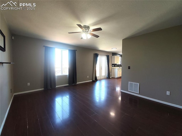 unfurnished room with a ceiling fan, visible vents, dark wood finished floors, and baseboards