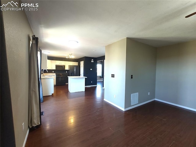 kitchen featuring dark wood finished floors, stainless steel microwave, black fridge with ice dispenser, visible vents, and white cabinets