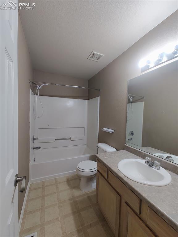 bathroom with toilet, visible vents, vanity,  shower combination, and tile patterned floors