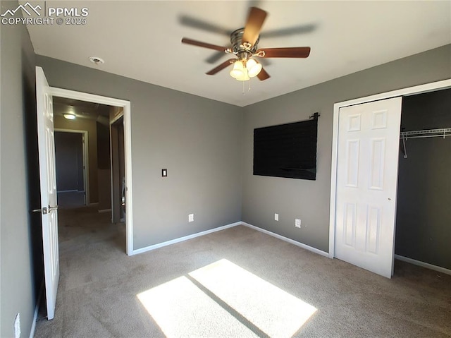 unfurnished bedroom with ceiling fan, a closet, baseboards, and carpet flooring