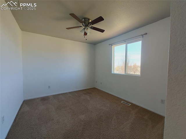 spare room featuring carpet floors, baseboards, visible vents, and a ceiling fan