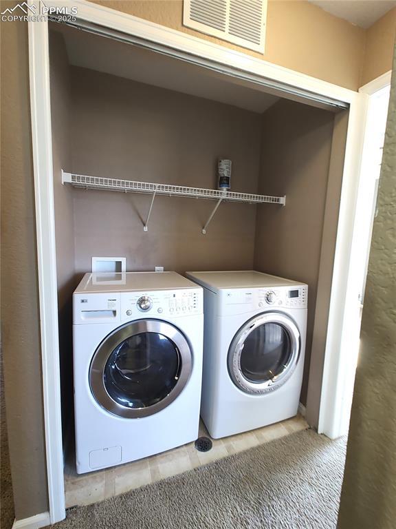 laundry area with carpet flooring, washing machine and dryer, and visible vents