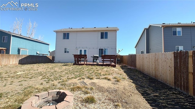 back of property with a fire pit, a yard, and a fenced backyard