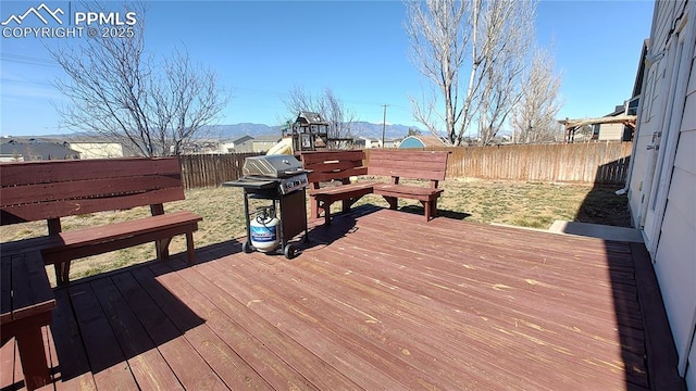 wooden terrace with grilling area and a fenced backyard