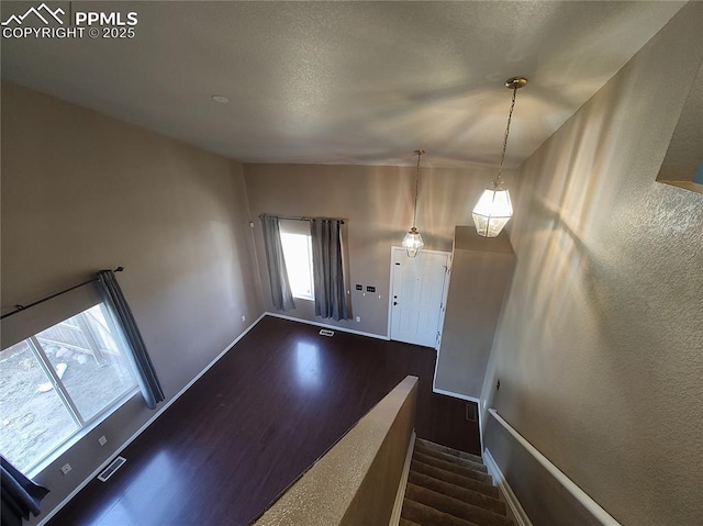 entrance foyer featuring a textured ceiling, a textured wall, dark wood-type flooring, and baseboards