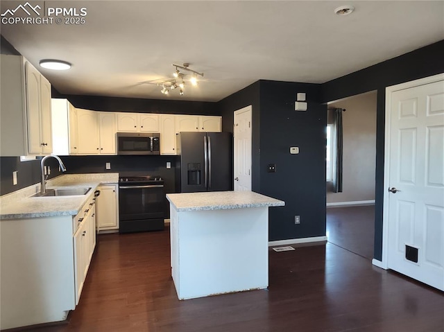 kitchen with a kitchen island, light countertops, black appliances, white cabinetry, and a sink