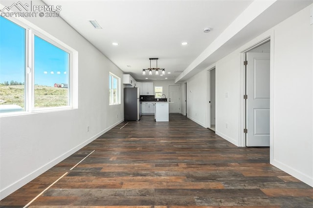 kitchen featuring dark wood-type flooring, visible vents, baseboards, white cabinets, and freestanding refrigerator