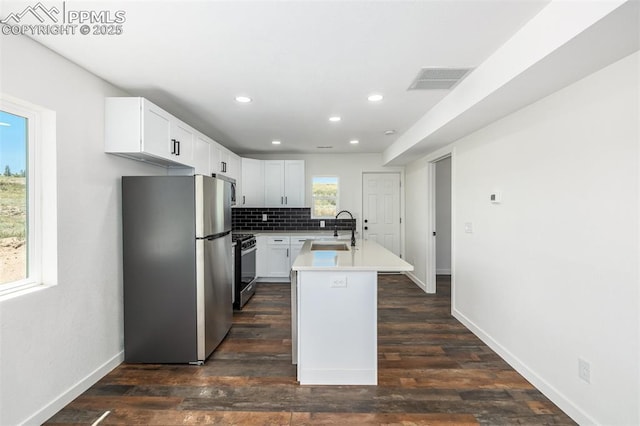 kitchen with decorative backsplash, range with gas stovetop, freestanding refrigerator, light countertops, and a sink