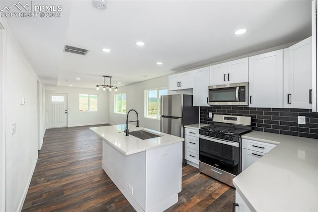 kitchen featuring dark wood finished floors, light countertops, backsplash, appliances with stainless steel finishes, and a sink