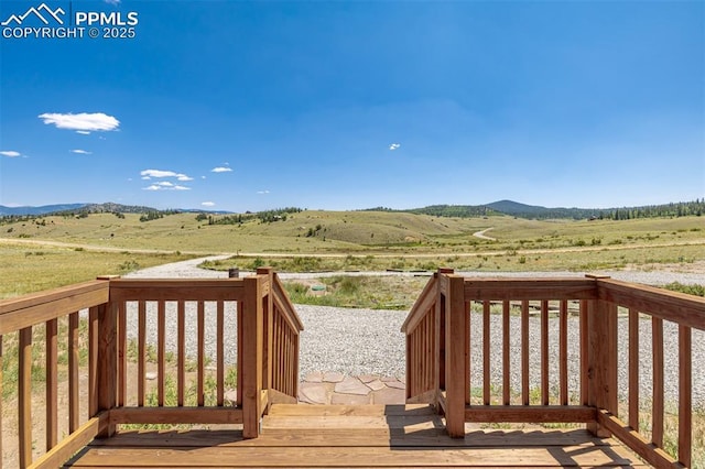 wooden terrace featuring a rural view and a mountain view