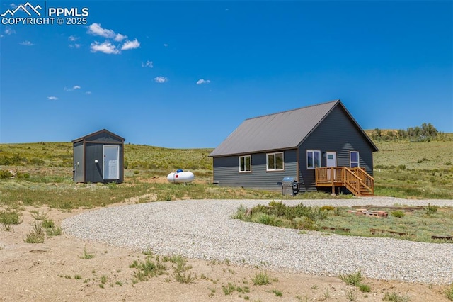 rear view of house featuring an outbuilding, a storage shed, and gravel driveway