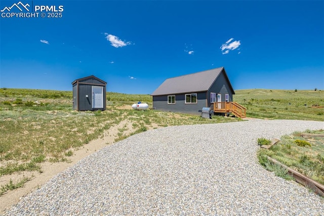 exterior space with gravel driveway, a storage unit, metal roof, and an outdoor structure