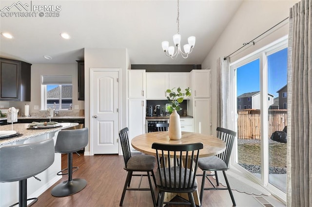 dining area featuring visible vents, lofted ceiling, wood finished floors, a notable chandelier, and recessed lighting