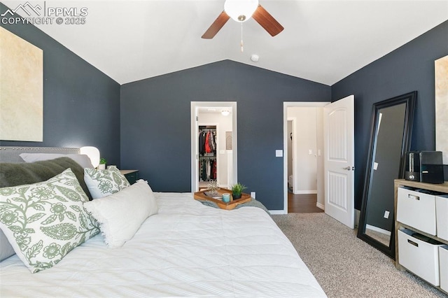 carpeted bedroom featuring a walk in closet, a closet, a ceiling fan, vaulted ceiling, and baseboards