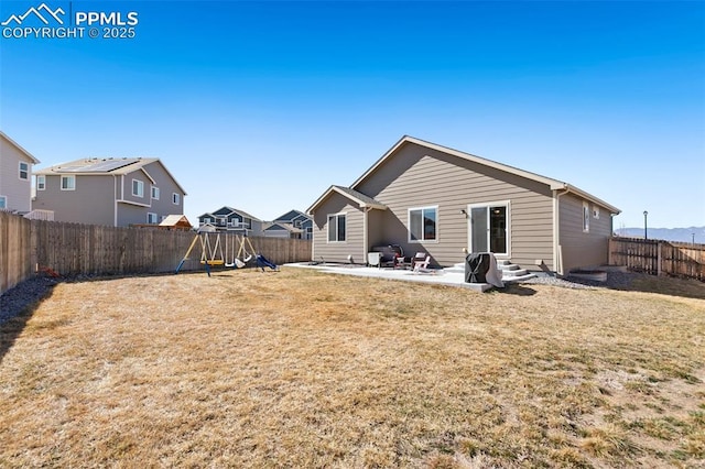 back of house with entry steps, a fenced backyard, a yard, a patio area, and a playground