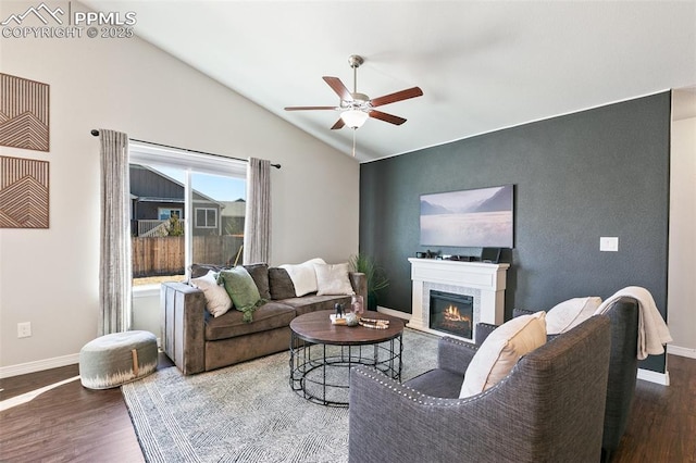 living room featuring lofted ceiling, a glass covered fireplace, baseboards, and wood finished floors