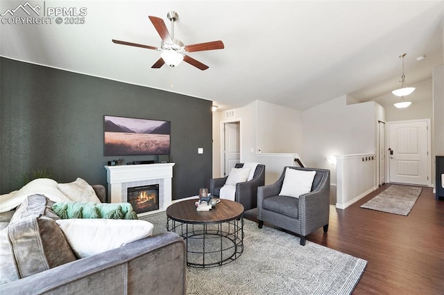 living room featuring baseboards, a glass covered fireplace, ceiling fan, wood finished floors, and vaulted ceiling