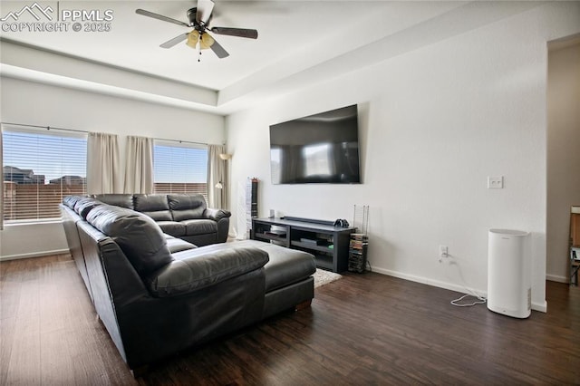 living area with a ceiling fan, baseboards, and dark wood-type flooring