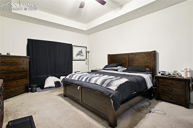 bedroom featuring carpet floors, a tray ceiling, and ceiling fan