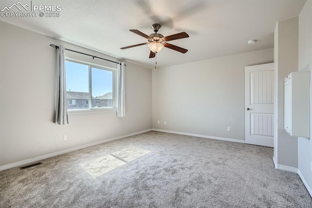 carpeted spare room featuring ceiling fan, visible vents, and baseboards