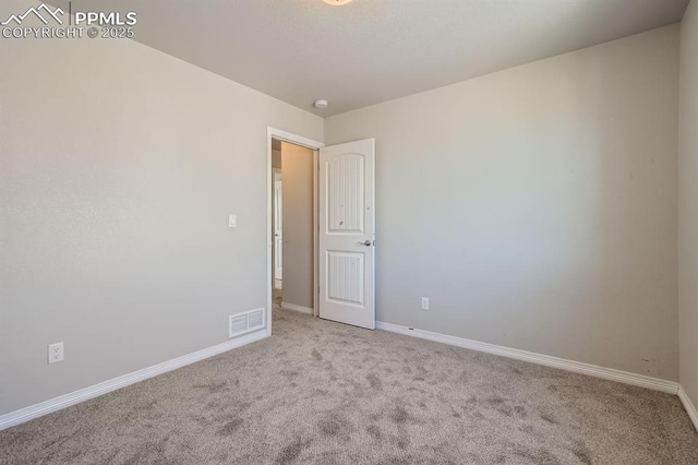 unfurnished room featuring baseboards, visible vents, and carpet flooring