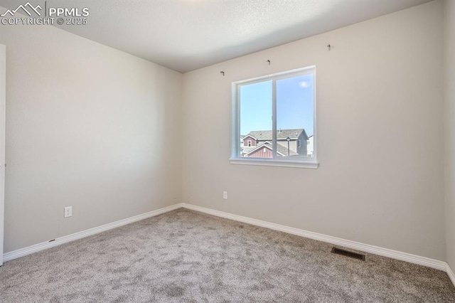 spare room featuring carpet floors, visible vents, and baseboards