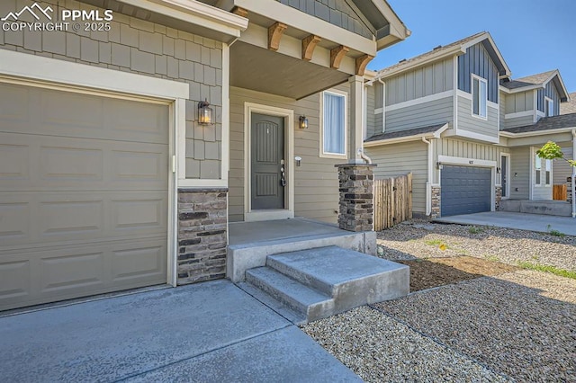 doorway to property with driveway, stone siding, and board and batten siding