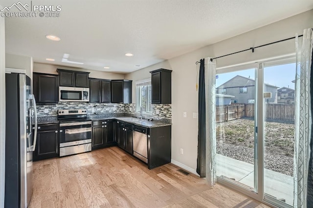 kitchen featuring tasteful backsplash, visible vents, stainless steel appliances, light wood-style floors, and a sink