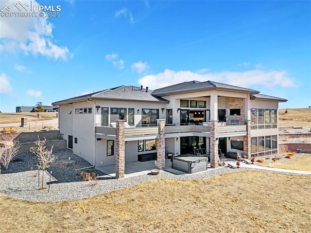 back of house featuring a patio area, a hot tub, a balcony, and stucco siding