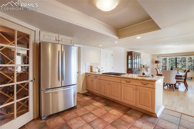 kitchen featuring a raised ceiling, appliances with stainless steel finishes, a peninsula, light stone countertops, and recessed lighting