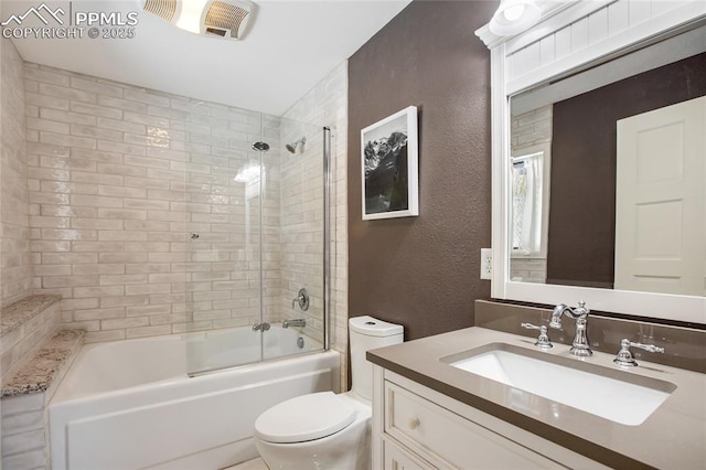 bathroom with toilet, vanity,  shower combination, and a textured wall