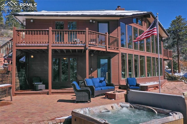 back of property with an outdoor living space with a fire pit, a patio area, an outdoor hot tub, and a wooden deck