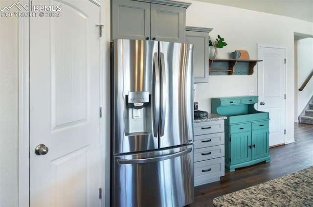 kitchen with open shelves, stone countertops, dark wood-style flooring, gray cabinetry, and stainless steel fridge