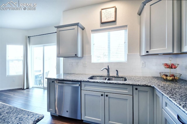 kitchen with tasteful backsplash, gray cabinetry, dishwasher, light stone counters, and a sink