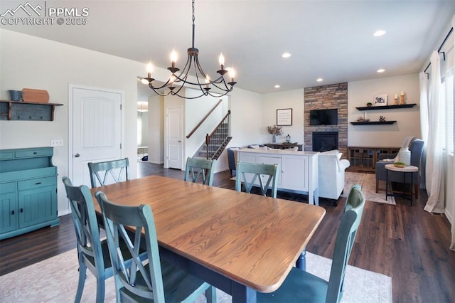 dining space with stairs, a stone fireplace, recessed lighting, a notable chandelier, and dark wood-style flooring