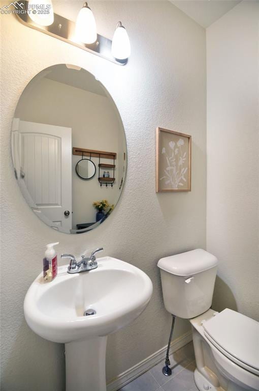 bathroom featuring tile patterned flooring, toilet, baseboards, and a sink