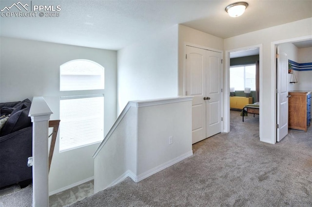 hall with baseboards, an upstairs landing, and carpet