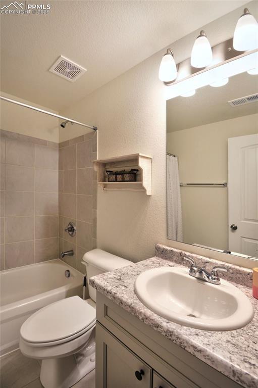 full bathroom with vanity, toilet, visible vents, and a textured ceiling