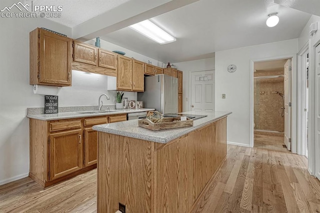 kitchen featuring light wood-type flooring, freestanding refrigerator, a sink, and dishwasher