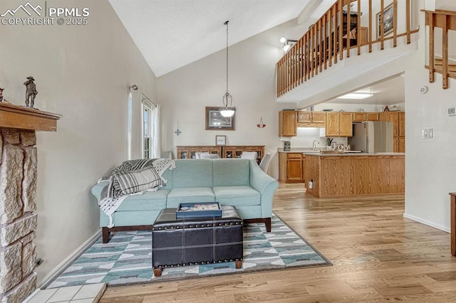 living room featuring high vaulted ceiling, light wood-type flooring, and baseboards