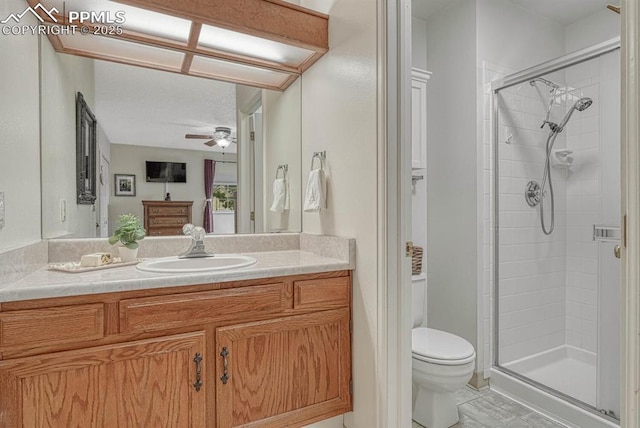 bathroom featuring a stall shower, vanity, toilet, and a ceiling fan