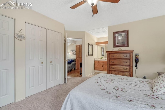 bedroom with a textured ceiling, light colored carpet, a ceiling fan, a closet, and attic access