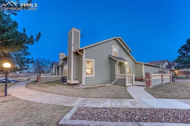 view of front of property featuring a fenced front yard, central AC, and a chimney