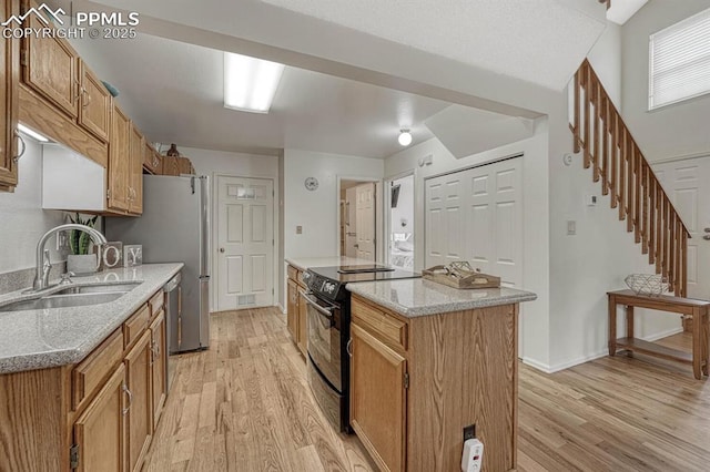 kitchen featuring light wood-type flooring, black electric range oven, a sink, and stainless steel dishwasher