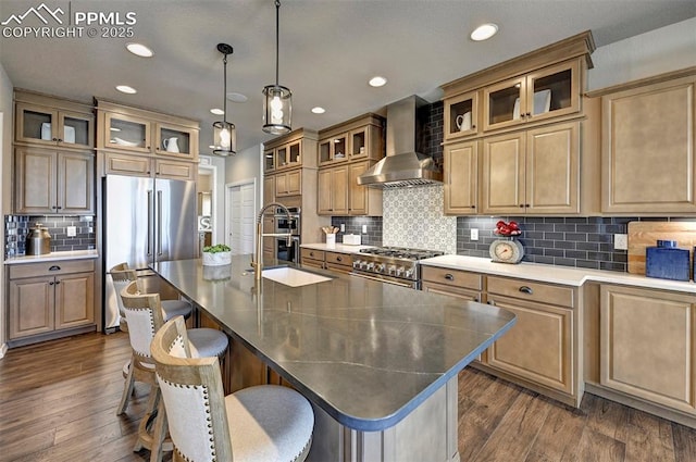 kitchen featuring an island with sink, wall chimney exhaust hood, high end appliances, and dark wood-style flooring